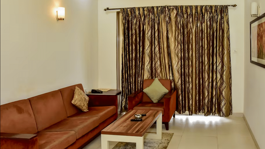 Spacious living area with cushioned sofa set, coffee table, curtained window, and warm lighting at La Vida Studio Inn.