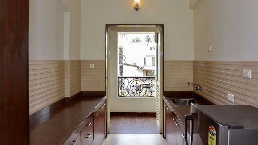 Kitchen corridor with fitted units and appliances at La Vida Studio Inn Goa.