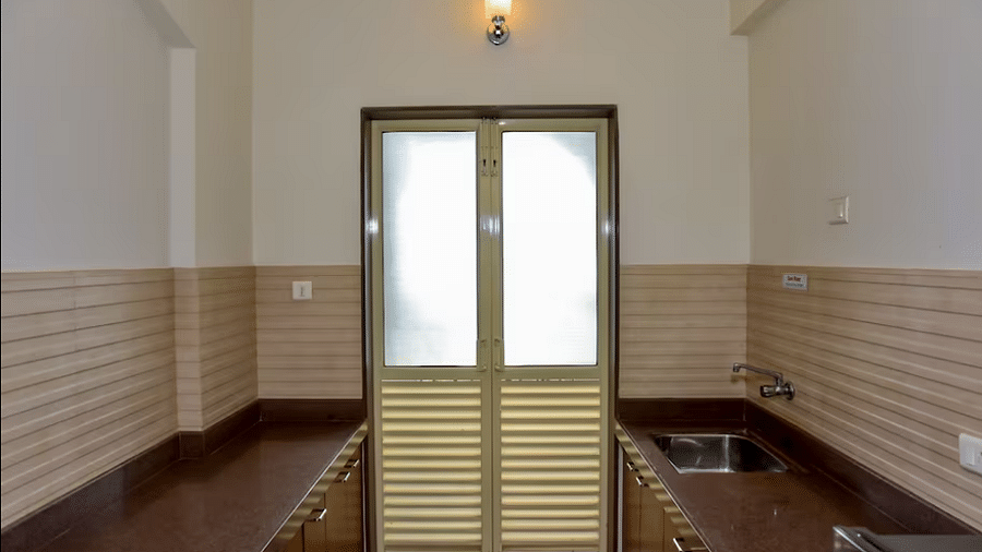 Kitchen area with tiled walls and a window at La Vida Studio Inn Goa.