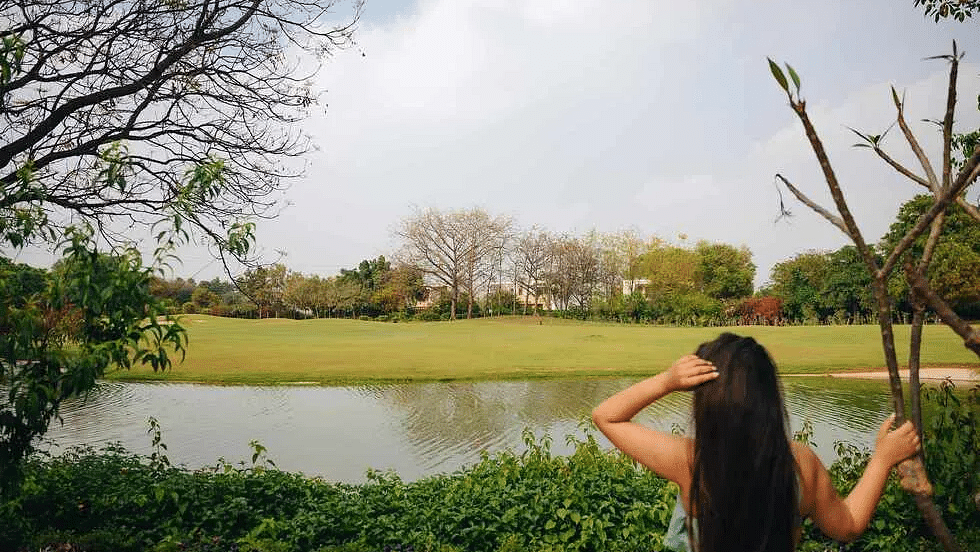 Woman taking a photo of a landscaped pond surrounded by greenery at Karma Chalets.