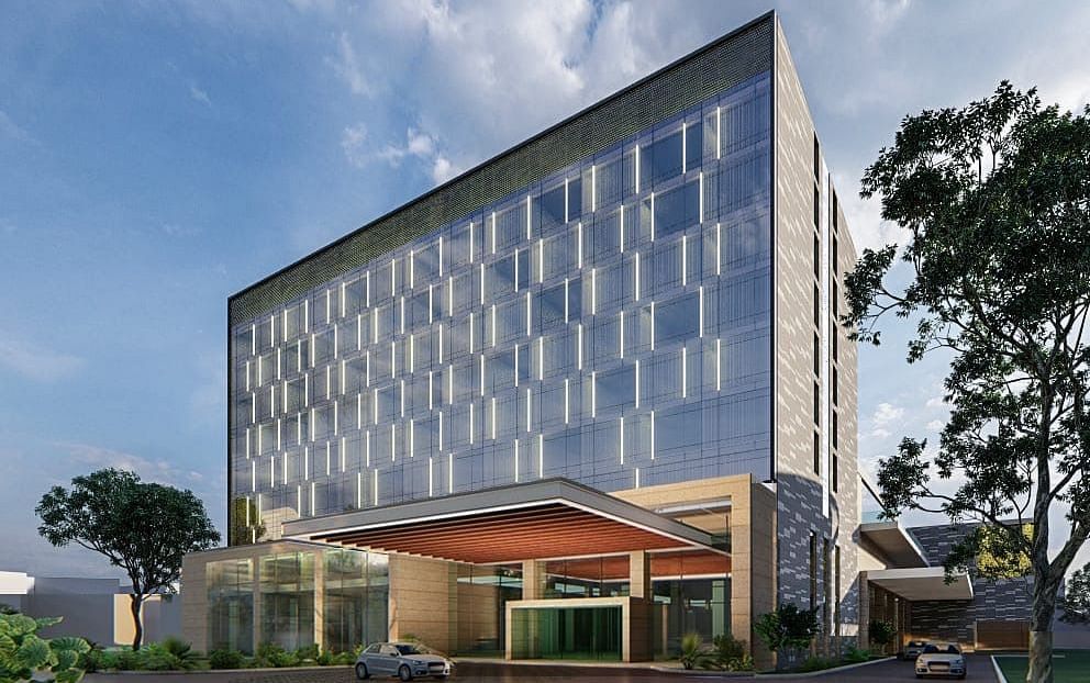 A facade of a building with trees and sky at Merlis Hotel, Coimbatore