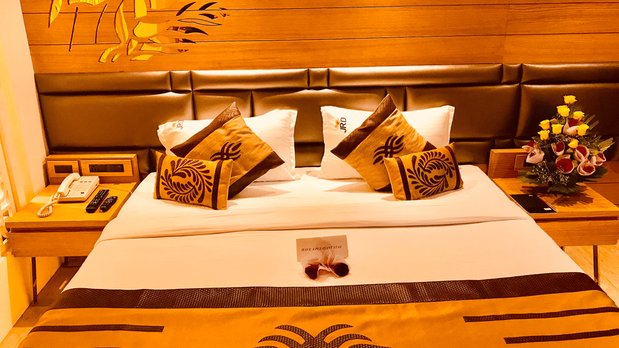 A Club Room at JRD Pride - Business Hotel featuring a neatly-made bed, matching cushions, an orange runner, and nightstands on either side of the bed.