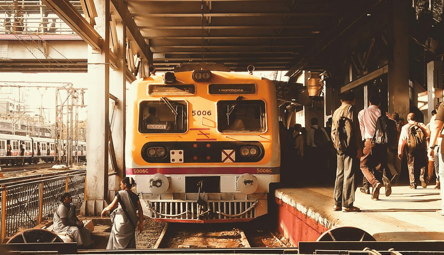 Image of a train on a track with people standing on the platform nearby.