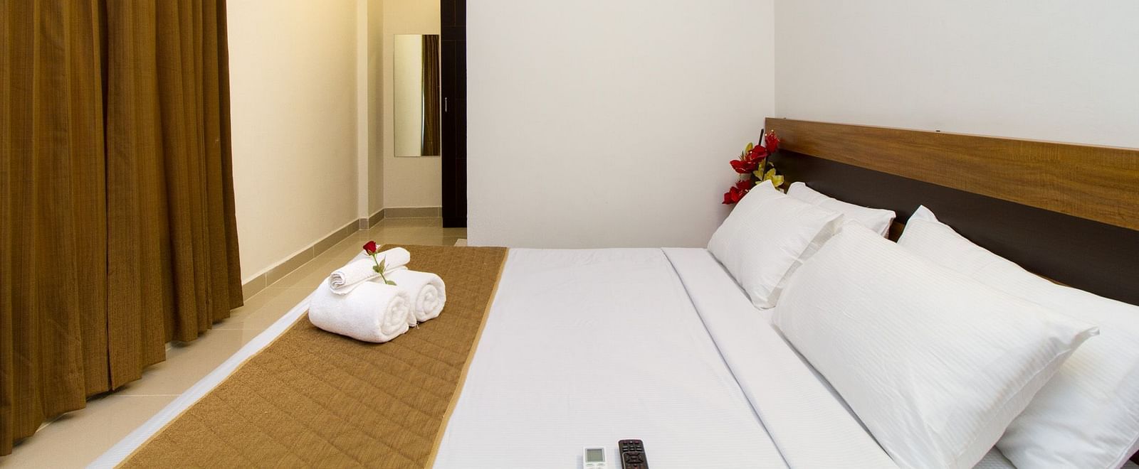 A room with a double bed and white and brown bedding at Sanctum Suites Whitefield, Bangalore.