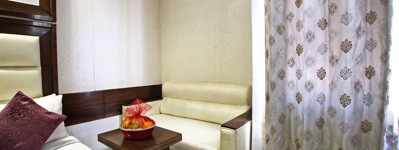 corner of a room with a sofa and a table and curtains
