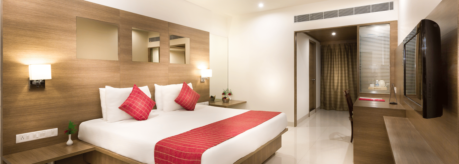 Bedroom featuring a plush bed at Regency Tiruttani by GRT Hotels, one of the best hotels in Tiruttani, under warm lighting facing the TV on the wall