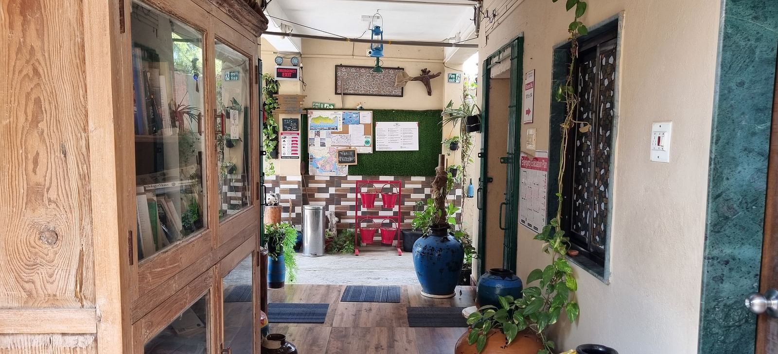 The corridor at the Dream Vision Guest House in Diu featuring a huge wooden cabinet along with several potted plants.