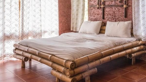  bedroom with a wooden bed frame, tan walls, and a window with patterned curtains.