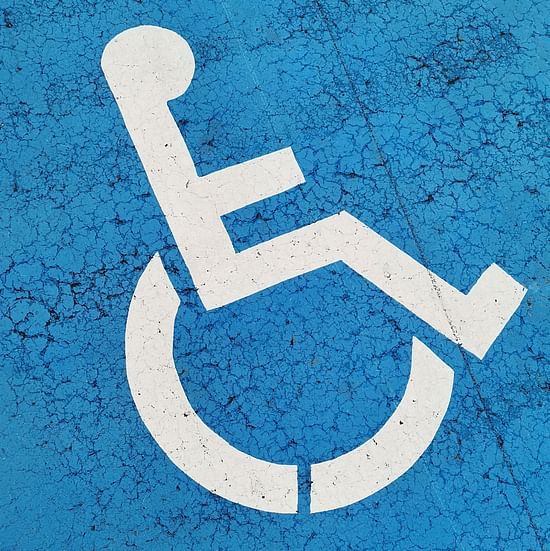 A white wheelchair symbol is painted on a blue textured surface.