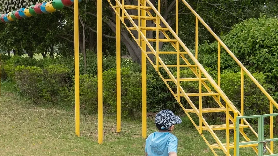 A child climbing a yellow metal slide structure in a grassy area at Karma Chalets.
