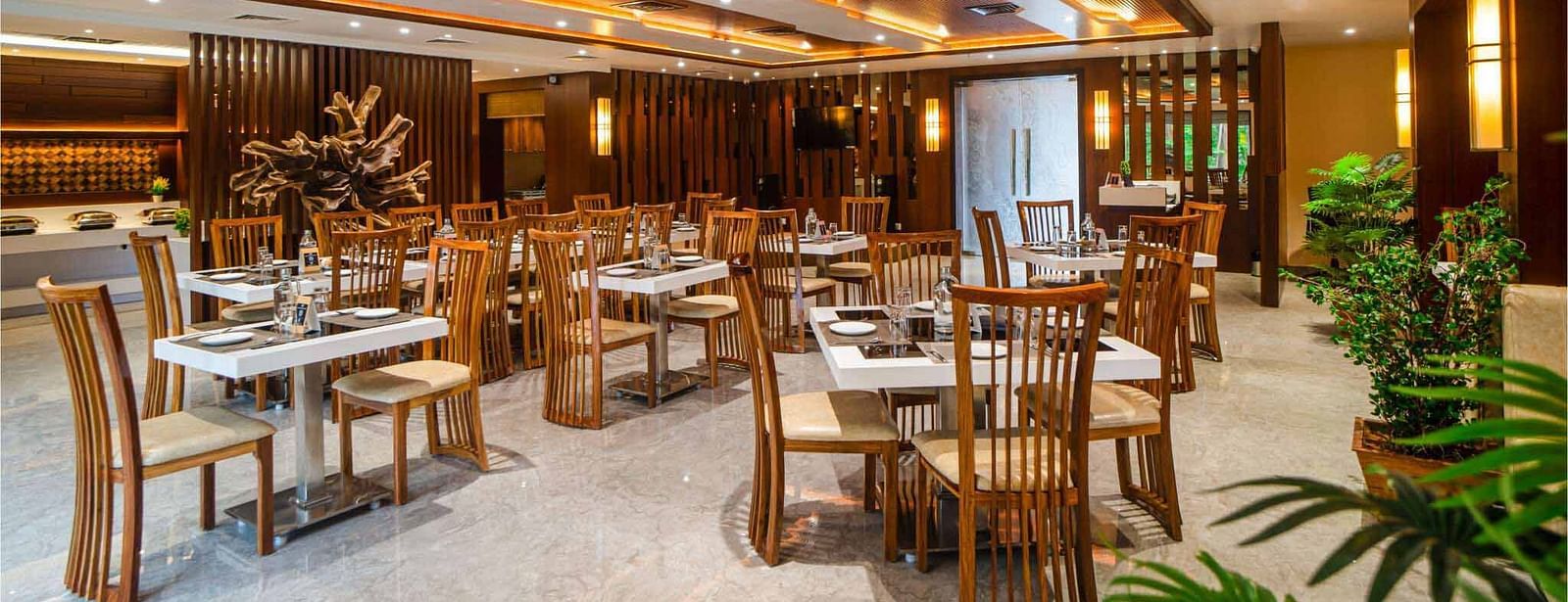 The inviting dining area at Mansha Palace features neatly arranged tables and comfortable wooden chairs.