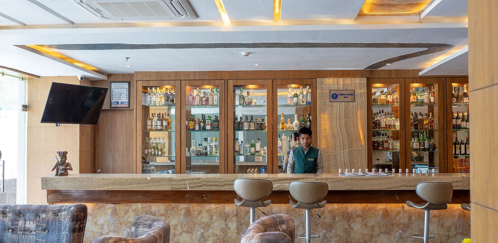 A lounge area with a long wooden bar counter with stools.