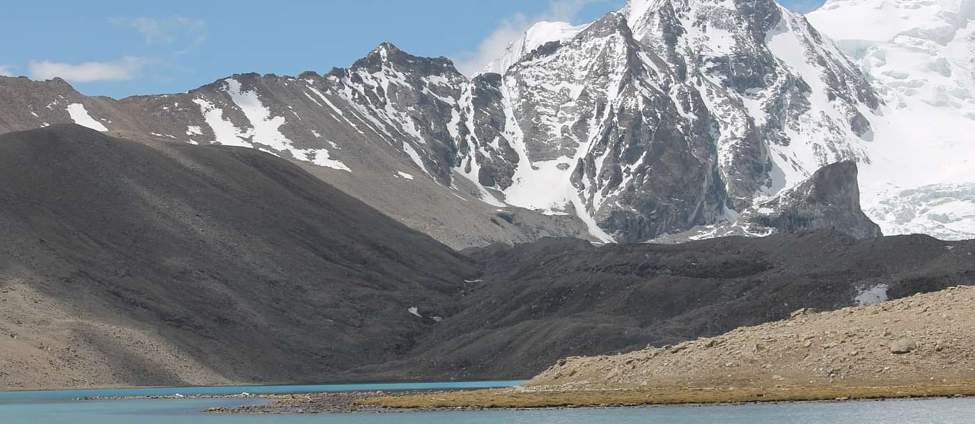 Image of a mountain range partially covered with snow and water body in the front