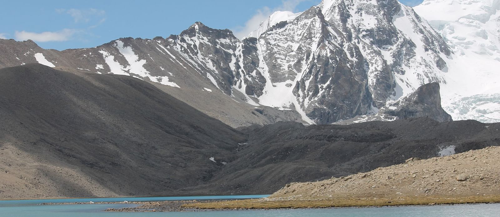 Image of a mountain range partially covered with snow and water body in the front