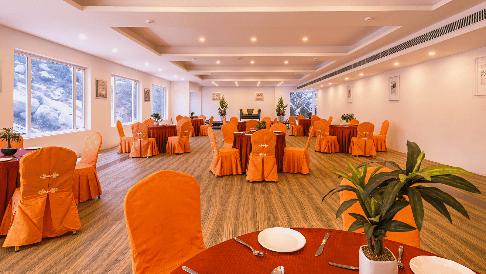 Another view of the spacious dining hall with orange chair covers and round tables set for a meal - TGI Grand Fortuna, Hosur