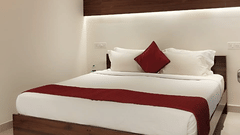 Modern bedroom with double bed, white walls, and minimal décor at Fantasy Golf Resort.