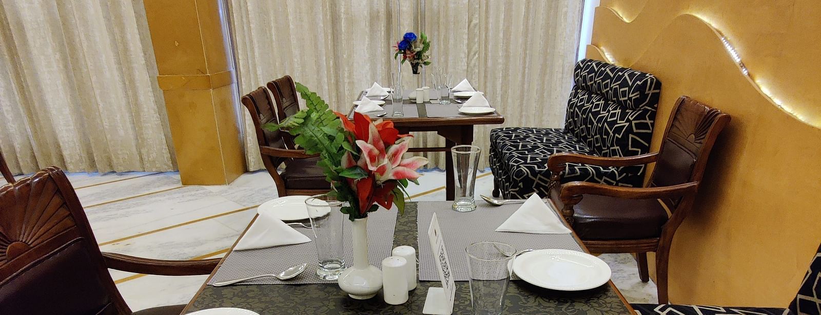 Close up shot of the dining table with table mats and plates along with cutlery and napkins arranged on the table - Hotel Gold, Panipat