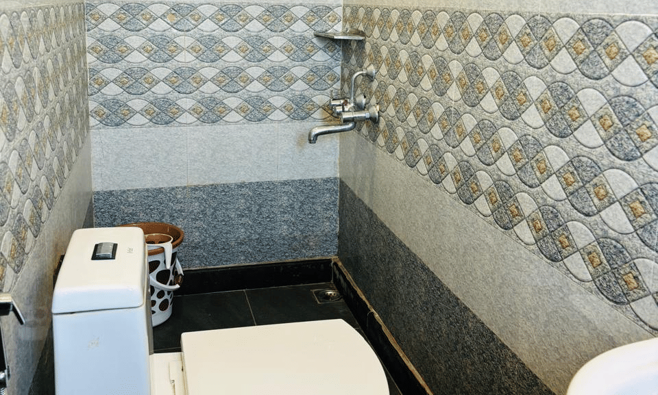 Bathroom with tiled walls, wash basin, mirror, and shower area at Paradise Lagoon Resort, Udupi.