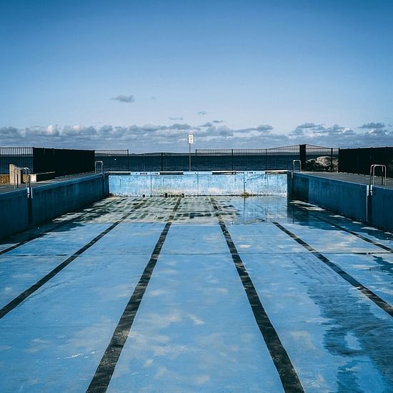 A concrete pier extending into calm water under a clear blue sky.