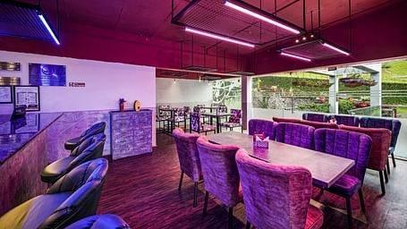 An image of a cafe with the seating arrangement and bright lighting - GReaT Trails Kodaikanal By GRT Hotels