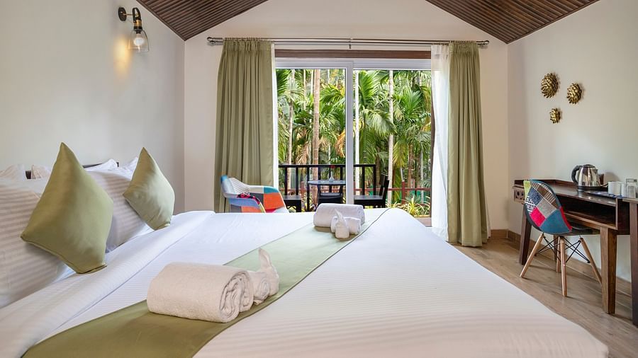 A hotel room featuring a king size bed, a workstation with a chair, and a view overlooking the pool - Stone Wood Nature Resort, Gokarna