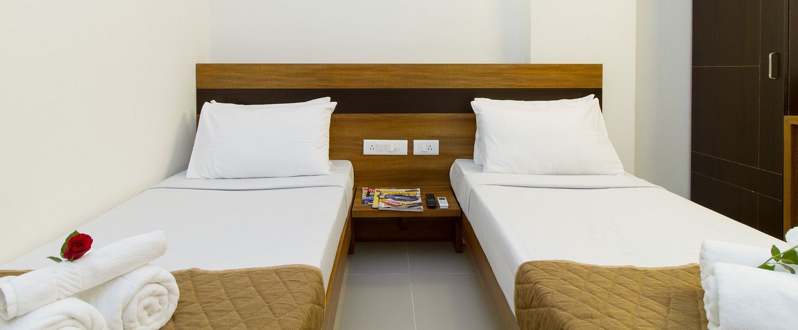 A hotel room at Sanctum Suites Whitefield, Bangalore presenting twin beds with white bedding and a wooden headboard.