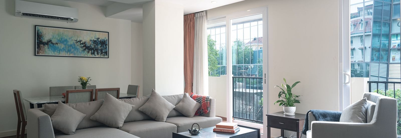 A living room with a sofa, a coffee table, an armchair, and a window with a view | Three-bedroom Suite | Central Mansions, Phnom Penh