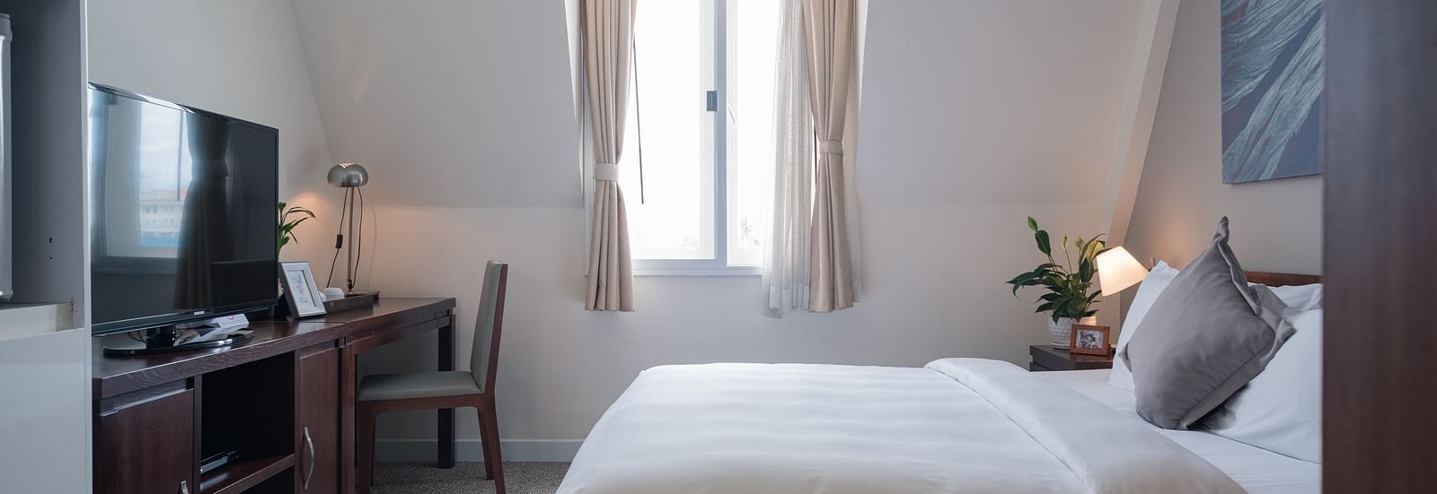 A bedroom with a bed, a desk, and a television | Studio | Central Mansions, Phnom Penh