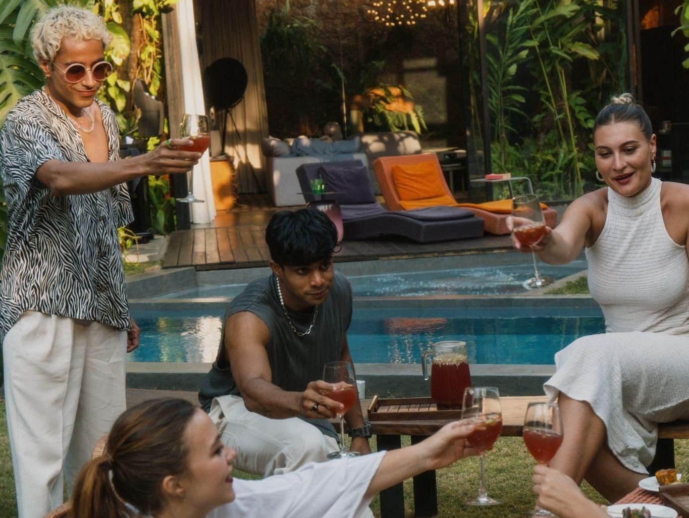 A picture of a few people having drinks next to a swimming pool