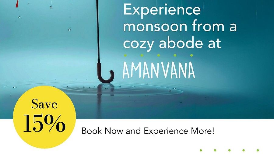 Orange umbrella in rain with water droplets against blue sky, advertising Amanvana Spa Resort, Coorgs monsoon experience with 15% discount offer
