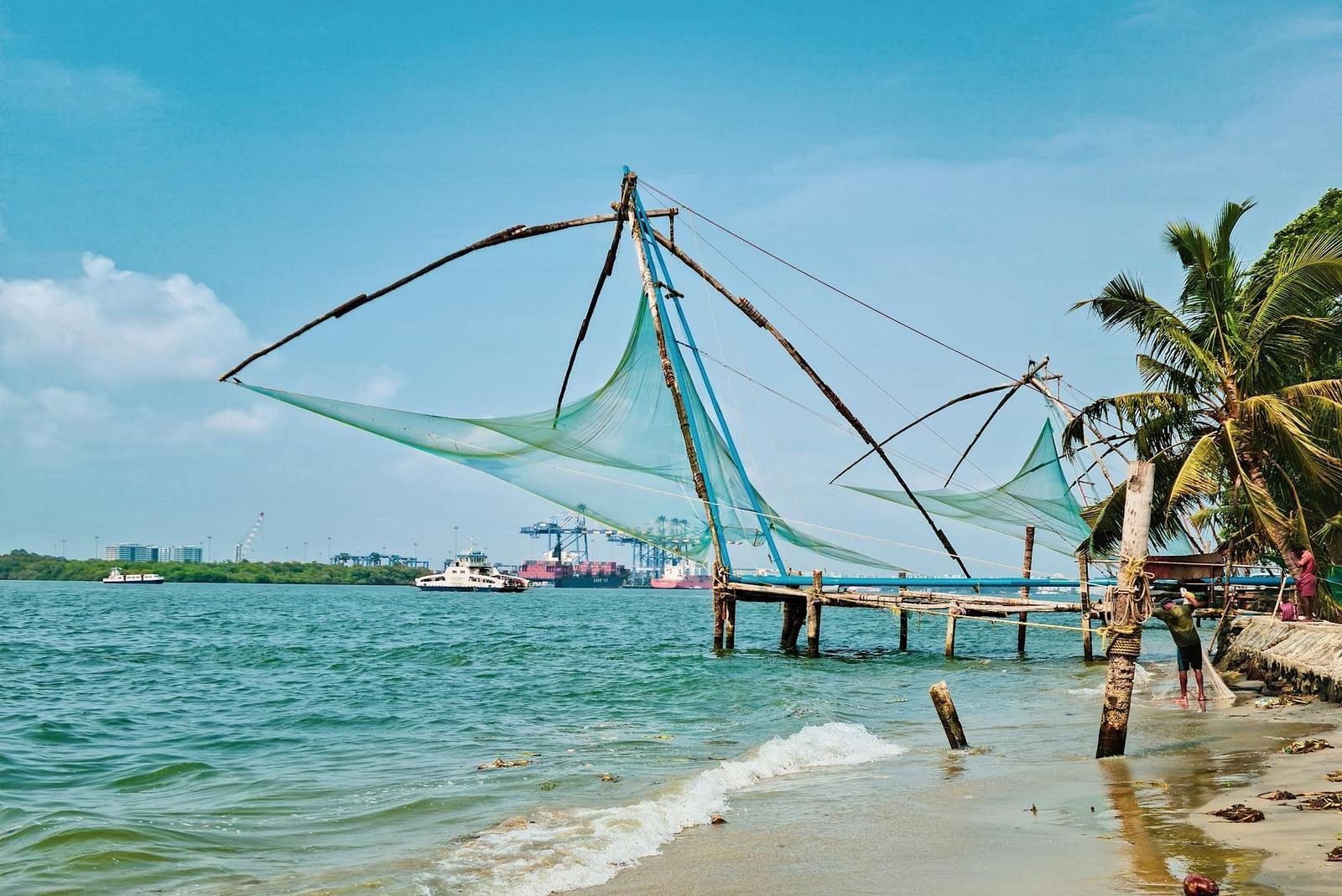 an image of a sea at Kochi with Chinese fish net with a dock surrounded by coconut trees.