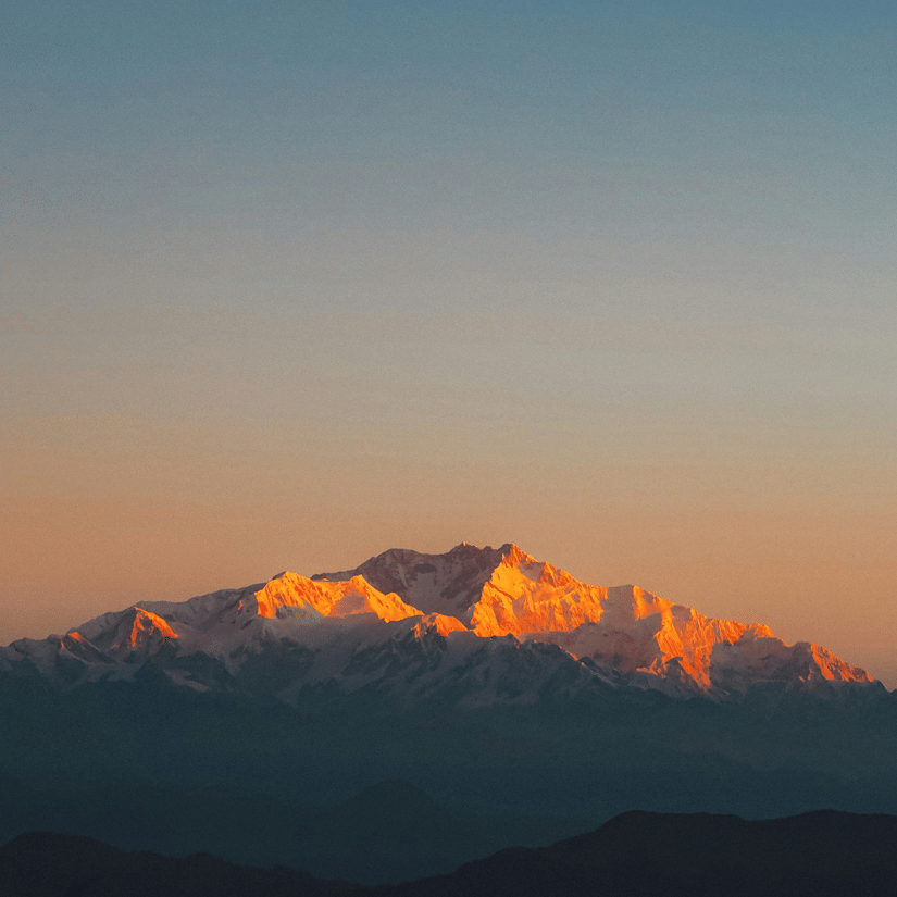 First light illuminating the Kanchenjunga mountain range as seen from Tiger Hill at sunrise.