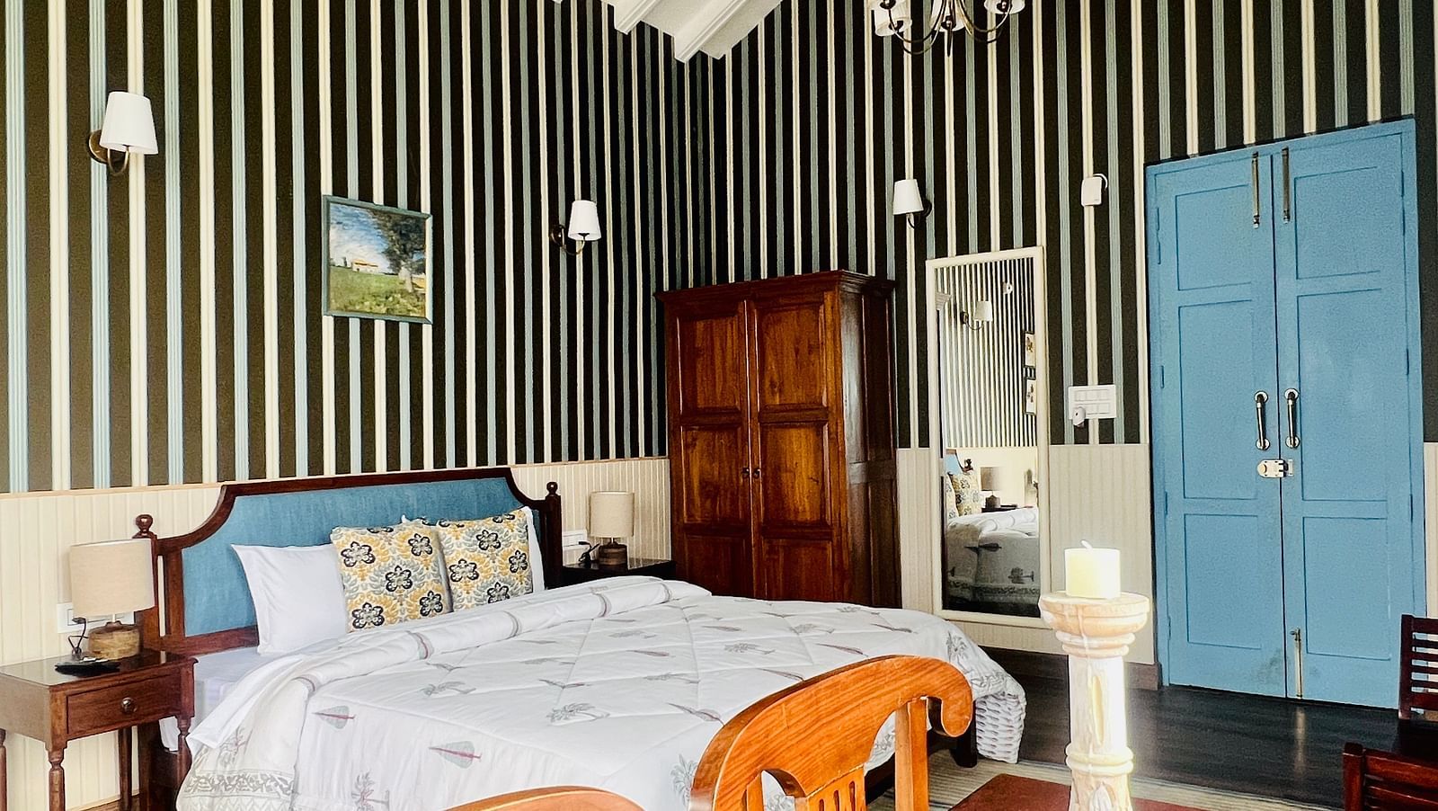 Elegant bedroom with striped wallpaper, wooden flooring, and a traditional wooden bed decorated with colorful cushions in a boutique hotel | Faraway Cottages, Auli