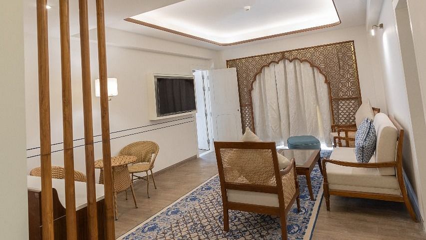 The living room at Ananta Room featuring the common seating area and an arched balcony at the far end covered with curtains at Bhagirathi by RDB Atishay.