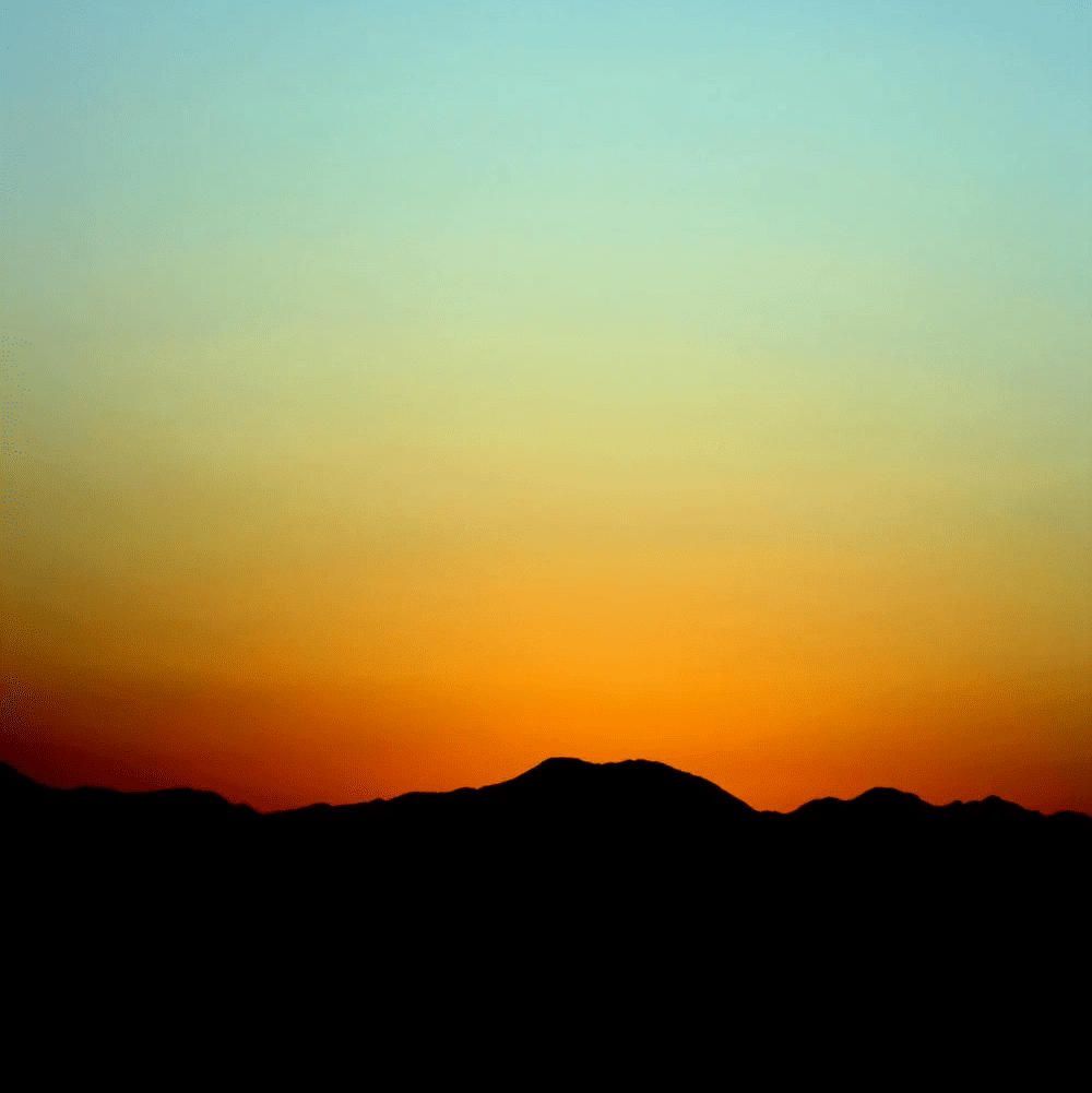 Image of sun setting behind the mountains.