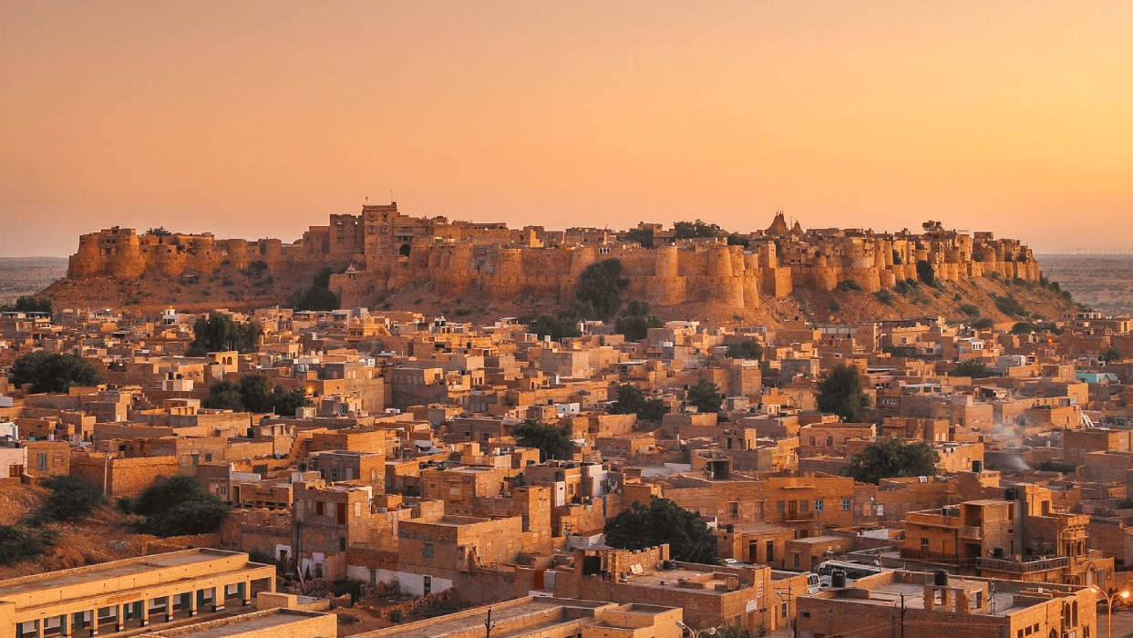 Golden hour panoramic view of the majestic Jaisalmer Fort towering over the traditional sandstone architecture of the city.