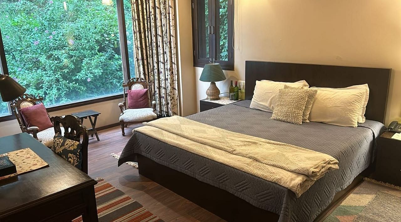A large bed next to a nightstand in one of the bedrooms in 2BHK at SOUTHGATE KASAULI BY ZENQ.