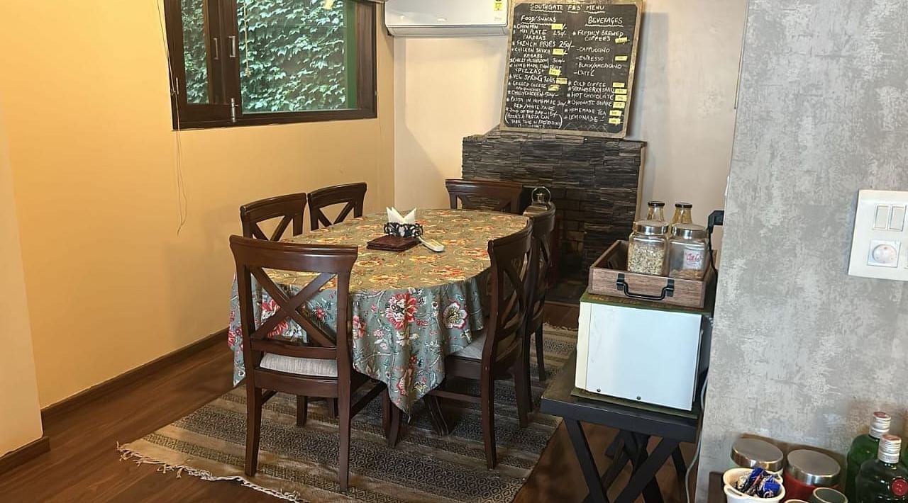A dining area in front of a wooden fireplace in 2 BHK at  SOUTHGATE KASAULI BY ZENQ.