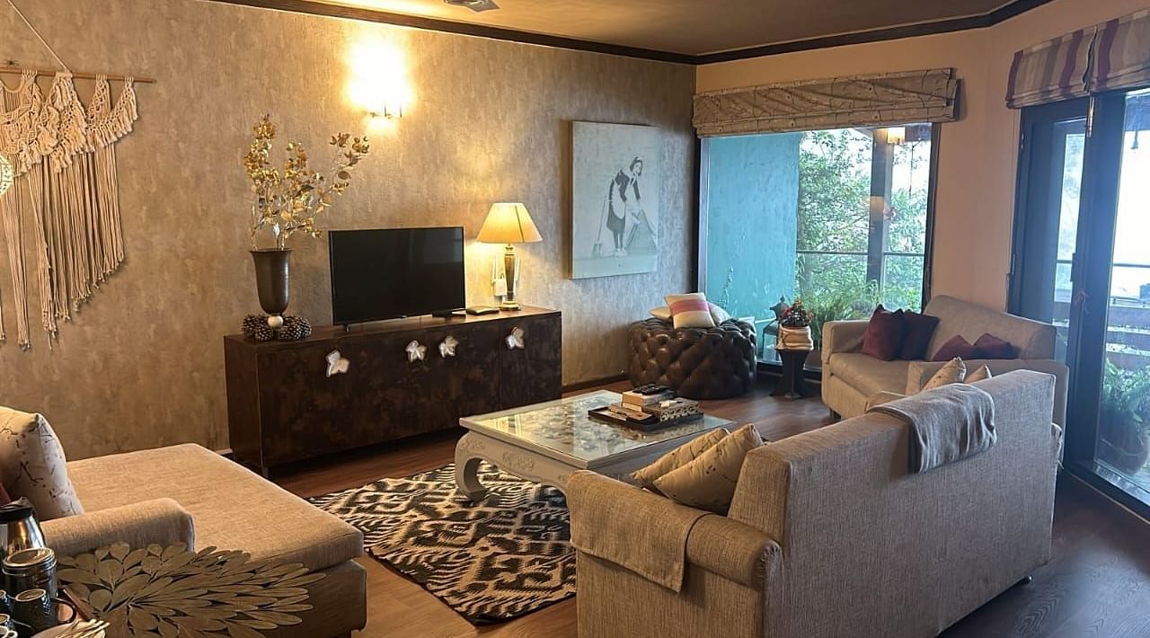 A living area with comfortable sofas in front of the TV at 2 BHK at at SOUTHGATE KASAULI BY ZENQ.