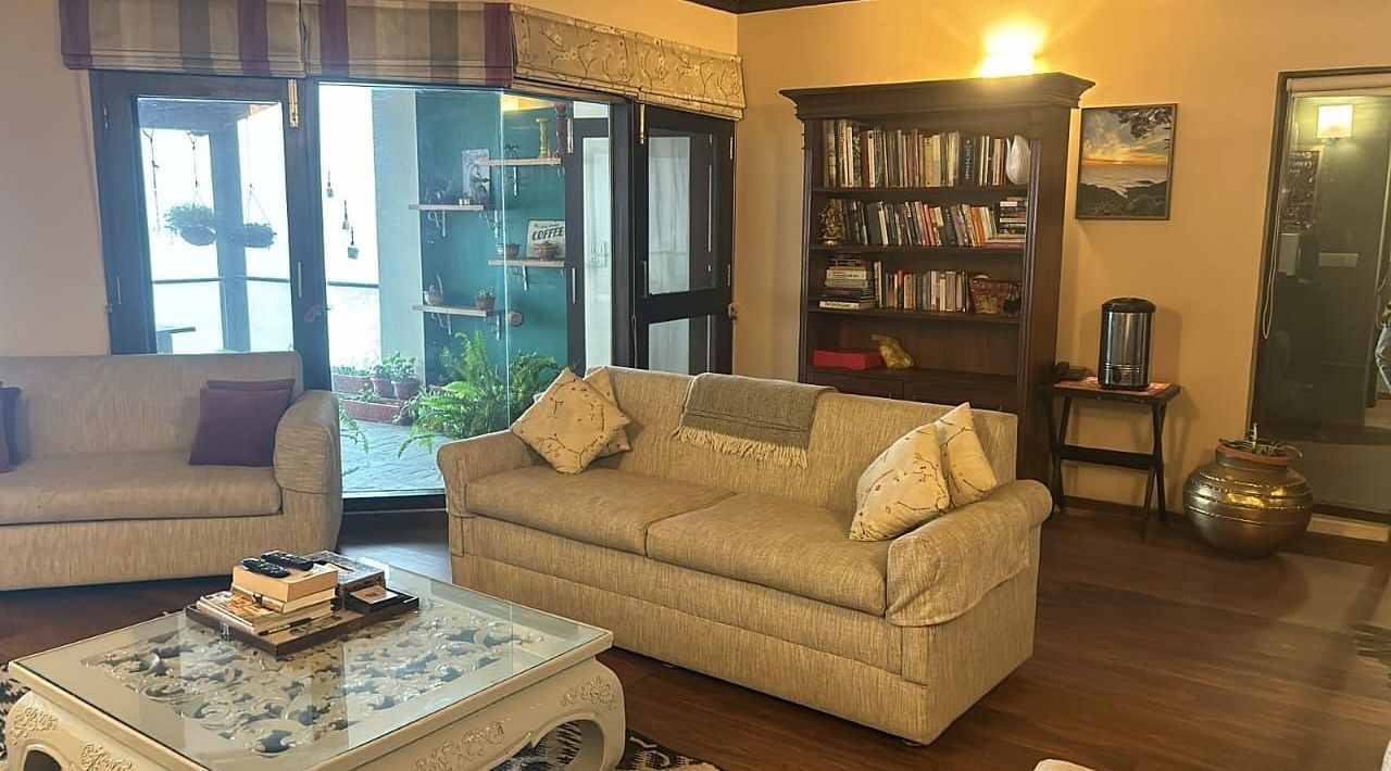 A living area with a comfortable sofa in front of a book case at 2 BHK at SOUTHGATE KASAULI BY ZENQ.