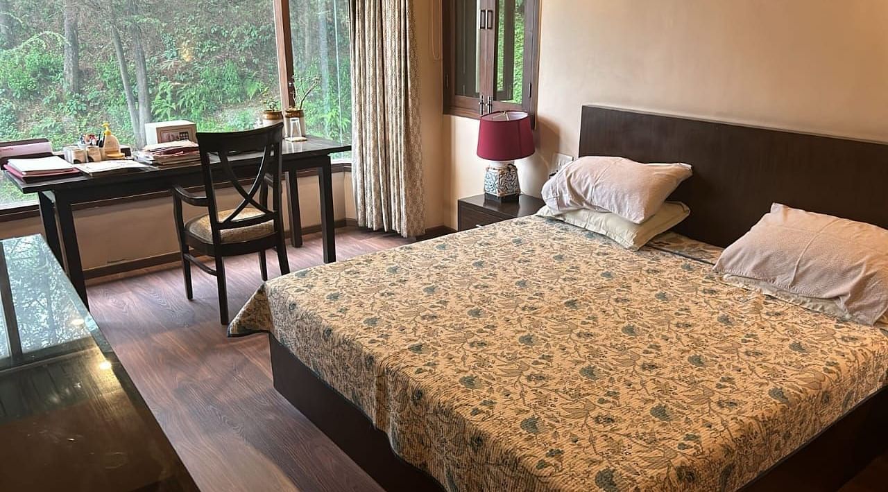 A large bed near a nightstand with a view of trees at Presidential Suite at SOUTHGATE KASAULI BY ZENQ.