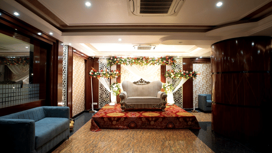 View of a banquet hall entrance at Five Elements Hotel with a blue sofa, decorative arch, floral garlands, and warm ambient lighting.