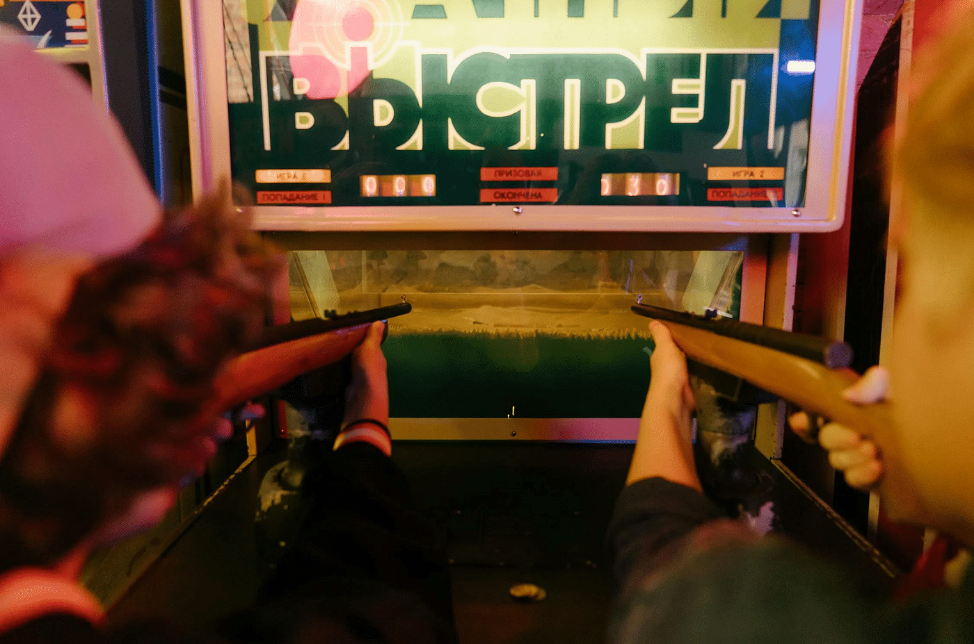 Two people with guns aiming at a screen in front of them.