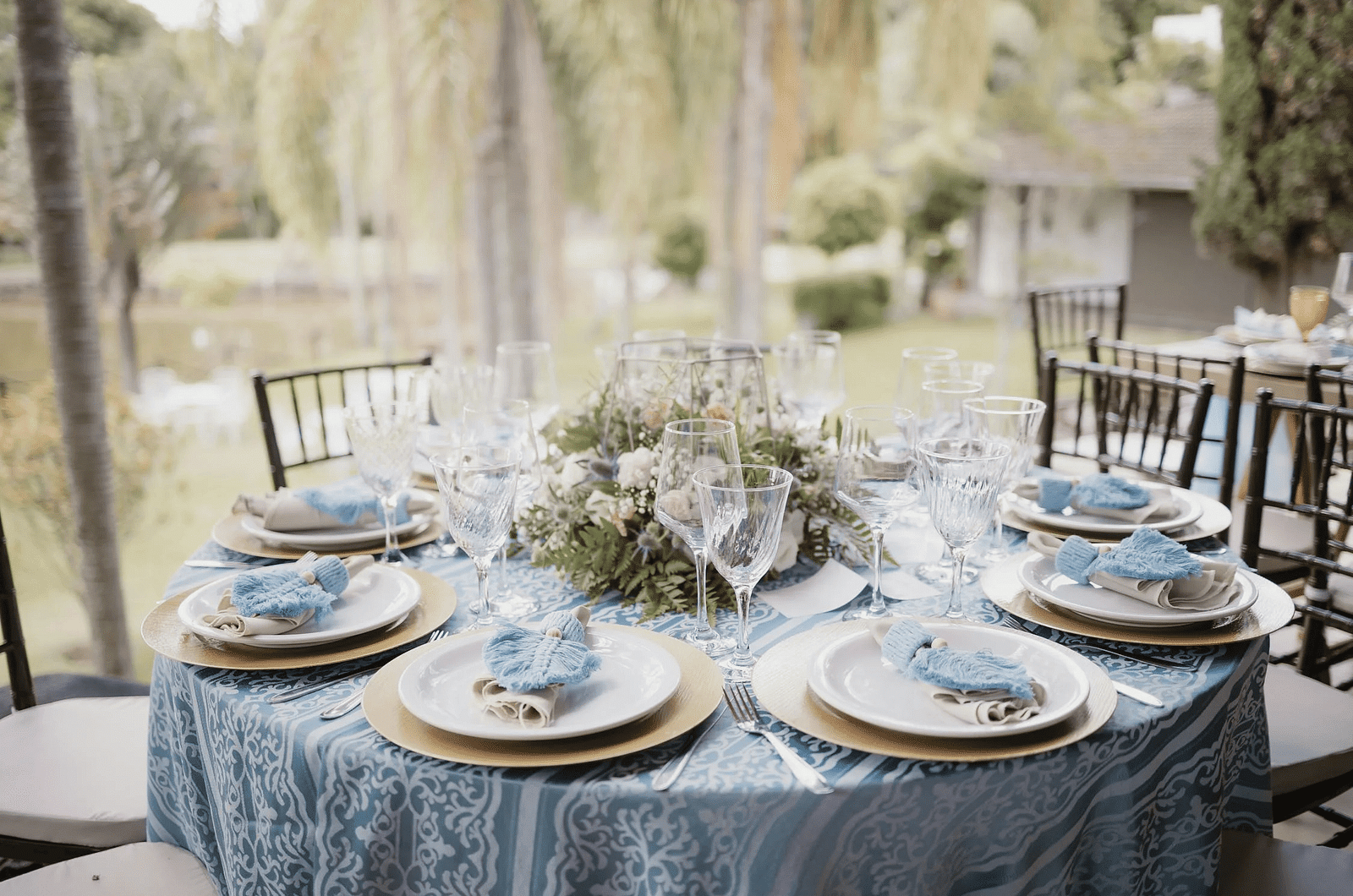A round table set with neatly arranged cutlery and a floral centerpiece.