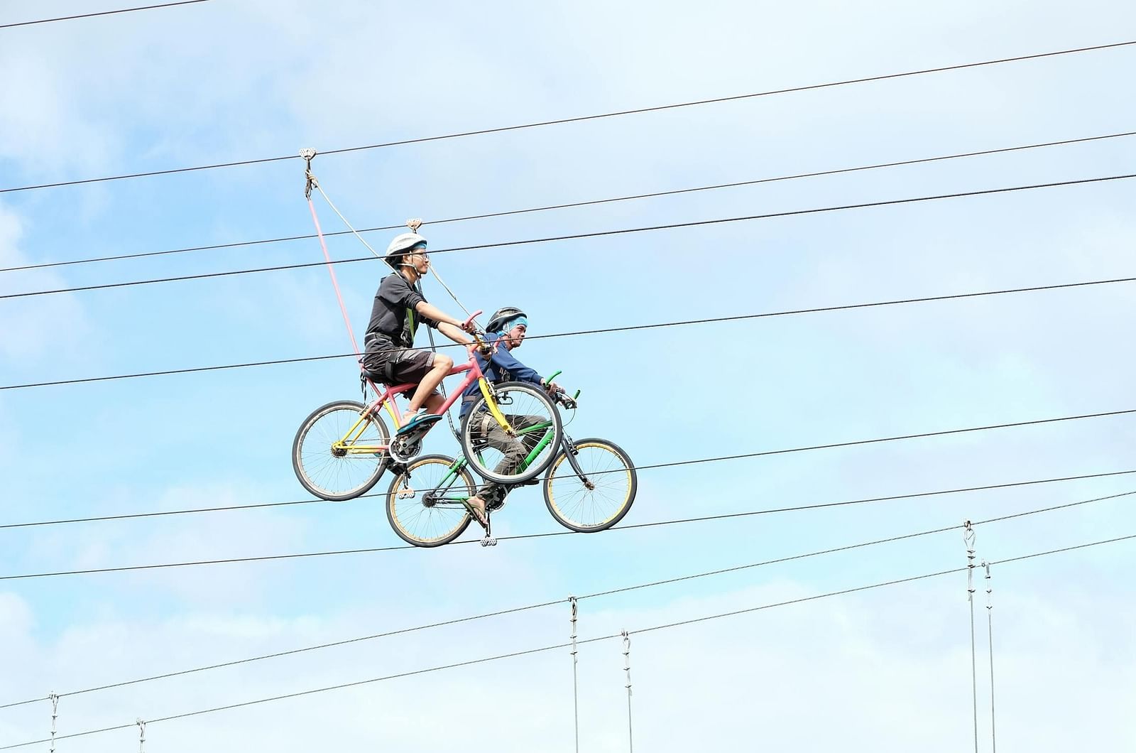 Two people on bicycles on a narrow track high above the ground.