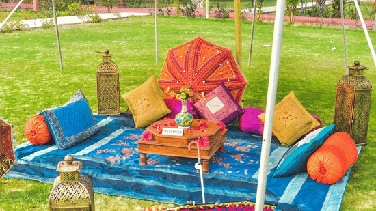 Colourful haldi or mehendi setup with vibrant cushions and décor at Umaid Palace lawn.