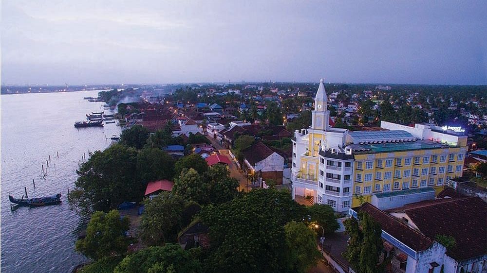 Aerial view of the hotel with the sky and beach in the background, surrounded by trees