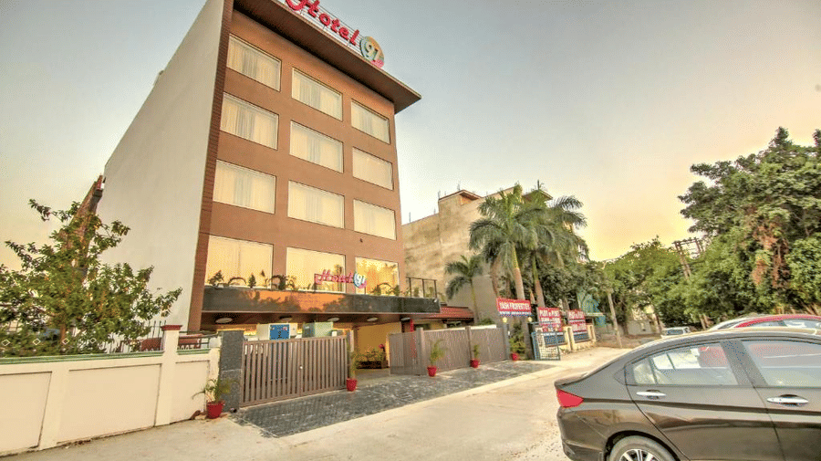 A perspective shot of the hotel building during dusk, showcasing the exterior lighting and the surrounding street view - Hotel 91 HUDA City Centre, Gurugram