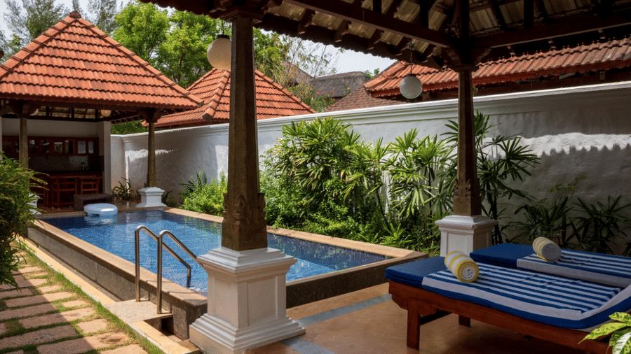 An outdoor private swimming pool area, featuring a tiled walkway, a sun lounger, and a gazebo | Le Pondy