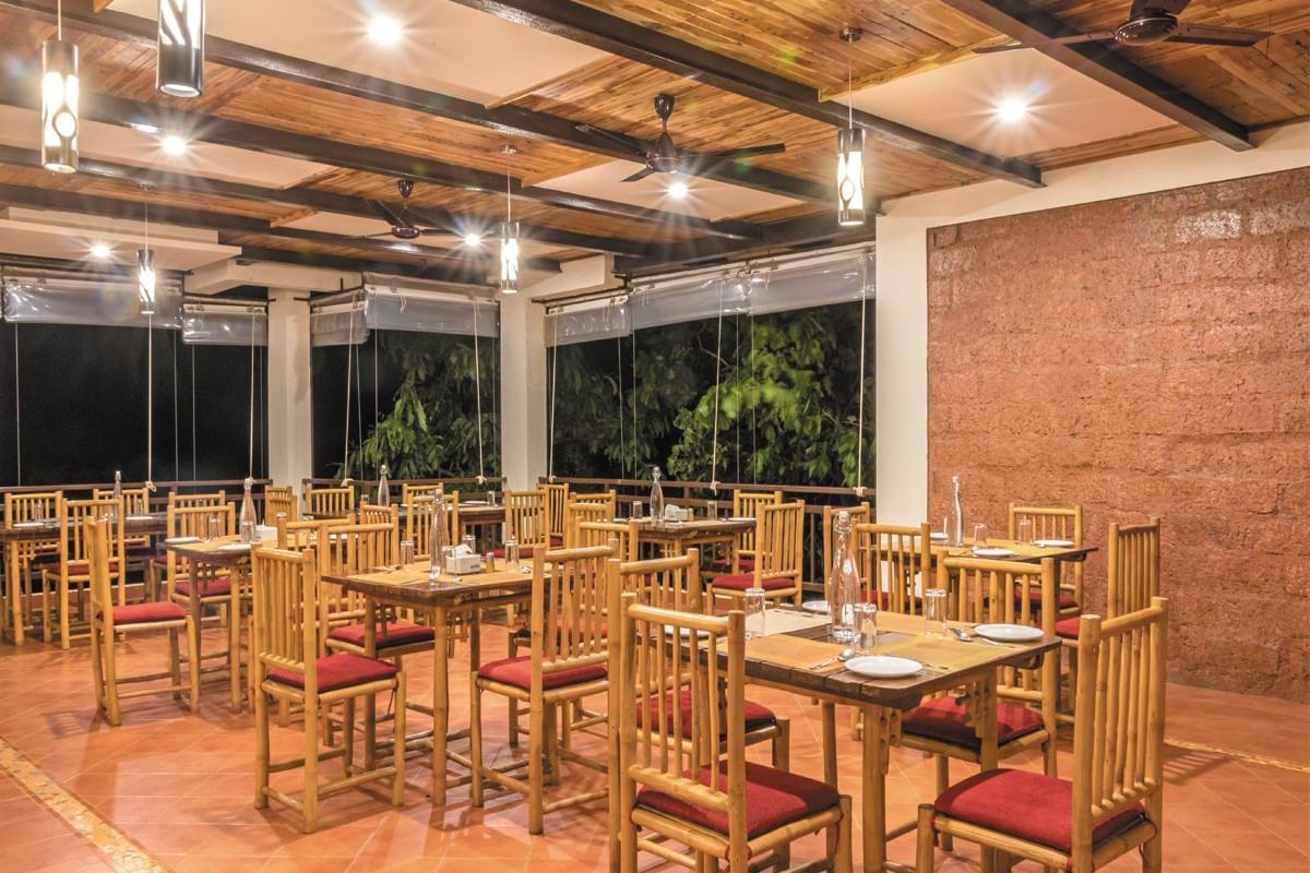 The spacious indoor dining area at Forest Escapes Koyna offers ample seating under bright lighting.